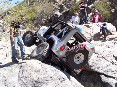 1981 Ford F-150 - A Jeep Wrangler struggles on a steep, rocky incline with onlookers observing the challenging off-road course.