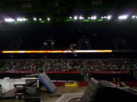 1986 Ford Bronco - A motocross rider performs a jump during an event inside a stadium with a large audience watching.