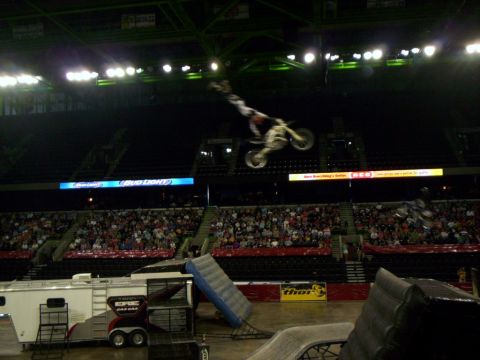 1986 Ford Bronco - A motocross rider performs a trick mid-air during an event in a stadium with a large crowd watching.