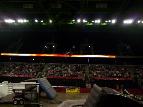 1986 Ford Bronco - A motocross rider performs a jump during an event in a stadium with spectators in the stands.