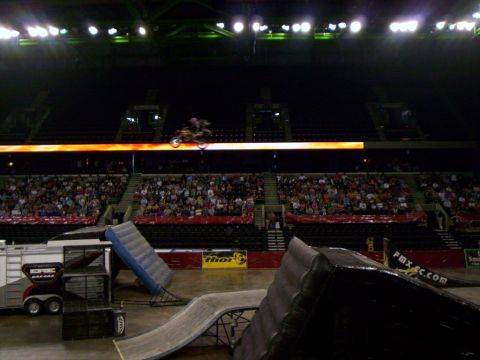 1986 Ford Bronco - A motocross rider performs a jump inside a stadium filled with spectators.