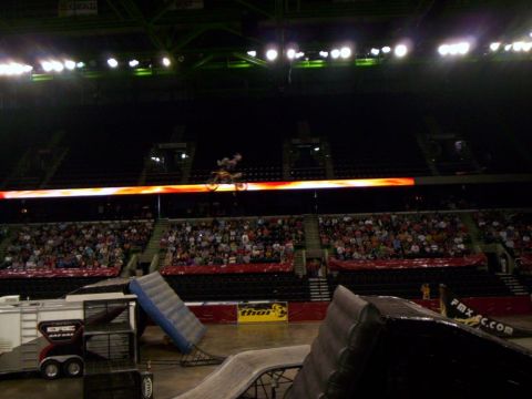 1986 Ford Bronco - A motocross rider performs a jump in a crowded arena, illuminated by stadium lights.