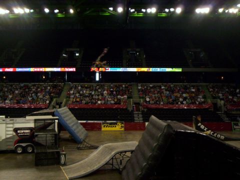 1986 Ford Bronco - A motorcycle rider soars through the air during a stunt show inside a packed arena.