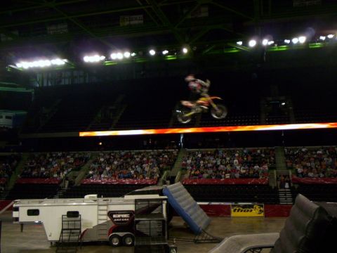 1986 Ford Bronco - Freestyle motocross rider launched high above an indoor arena floor on a red and white dirt bike, body extended off the seat mid-trick. Bel…