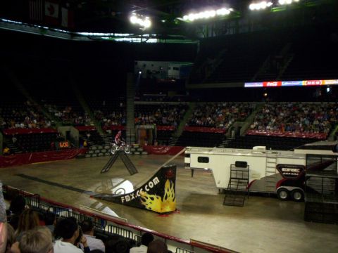 1986 Ford Bronco - Motocross event in an arena with a rider on a ramp and spectators in the stands.