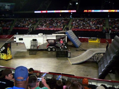 1986 Ford Bronco - A stunt show is set up in an arena with a BMX rider preparing to go down a ramp.