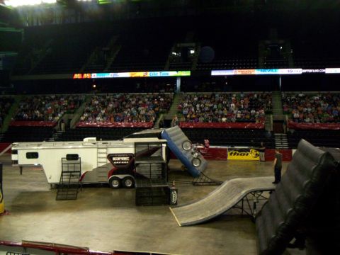 1986 Ford Bronco - Arena floor view of a freestyle motocross setup: a white gooseneck race trailer with red graphics and Gas Gas team lettering parked as a ra…