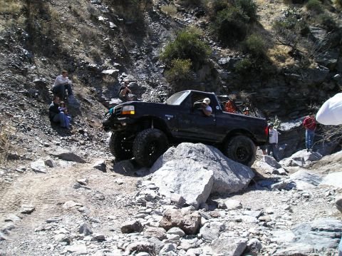 1993 Ford Bronco - This modified Ford Bronco is tackling a challenging off-road course with steep inclines and large boulders.