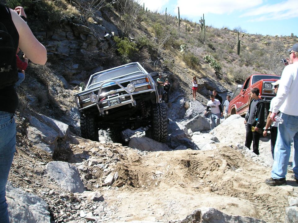 Off-road vehicles on a rocky trail with spectators