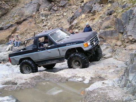 1993 Ford Bronco - This modified Ford Bronco is tackling a challenging off-road course with spectators watching.