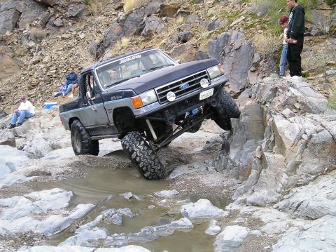 1993 Ford Bronco - This modified pickup truck is shown off-roading over rocks and through puddles.
