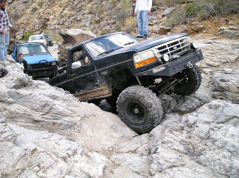 1993 Ford Bronco - This modified Ford F-150 is shown off-roading on a rocky trail with another vehicle following.