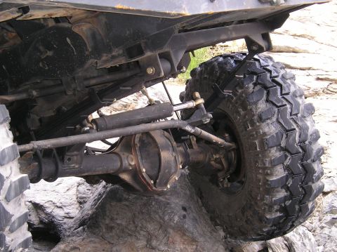 1993 Ford Bronco - Close-up view of the rear axle and tire of an off-road vehicle navigating rocky terrain.