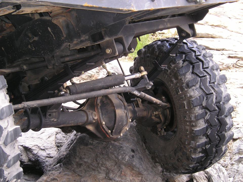 Off-road vehicle rear axle and large knobby tire on rocky terrain