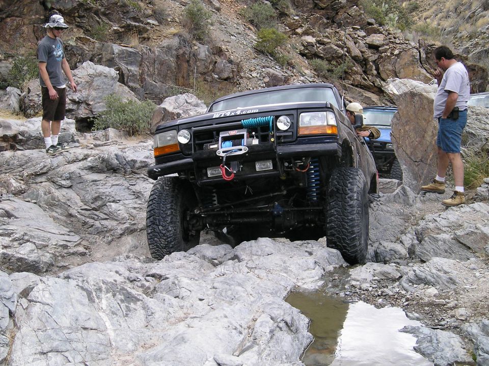 1993 Ford Bronco navigating a rocky trail with a second vehicle visible behind it