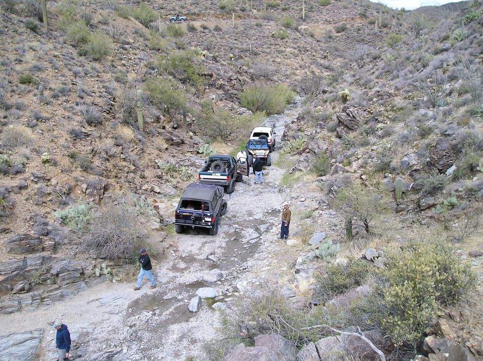 Black SUV and other off-road vehicles on a rocky, desert trail