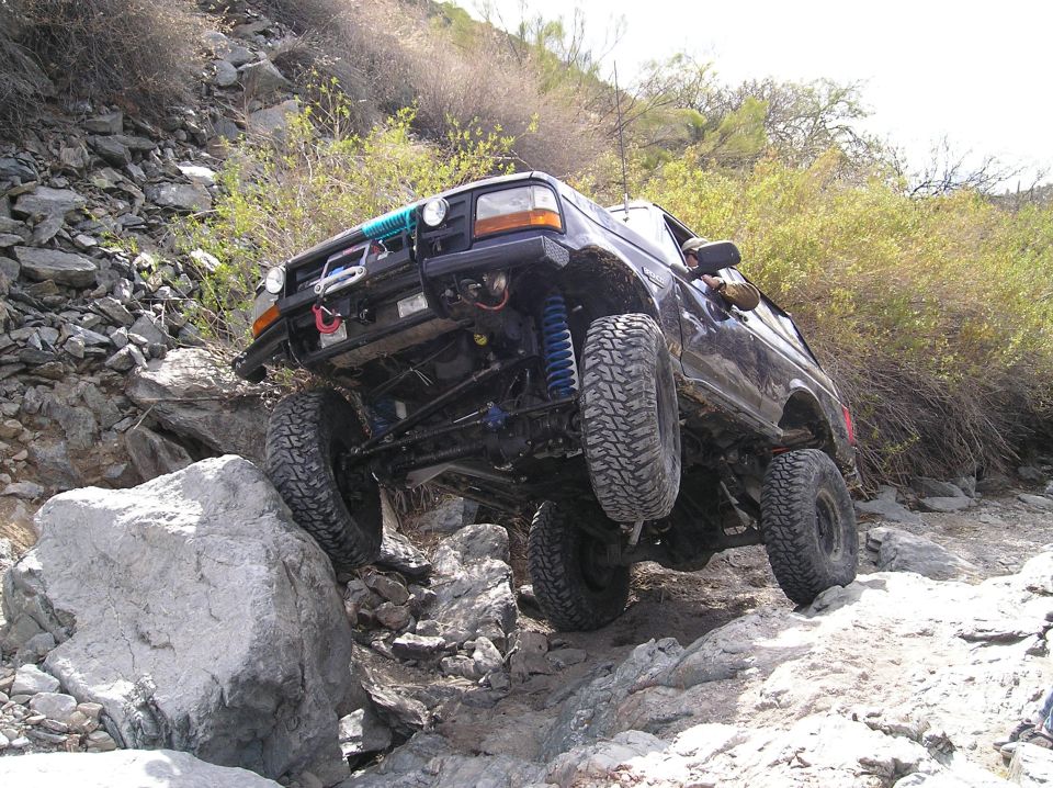 Black SUV with lifted suspension crawling over rocks