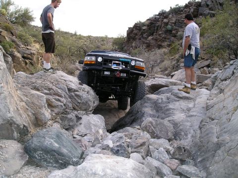 1993 Ford Bronco - An off-road SUV navigates a challenging rocky path in a desert canyon.