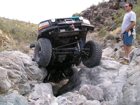 1993 Ford Bronco - A 1993 Ford Bronco tackles a challenging rocky trail with a man observing.