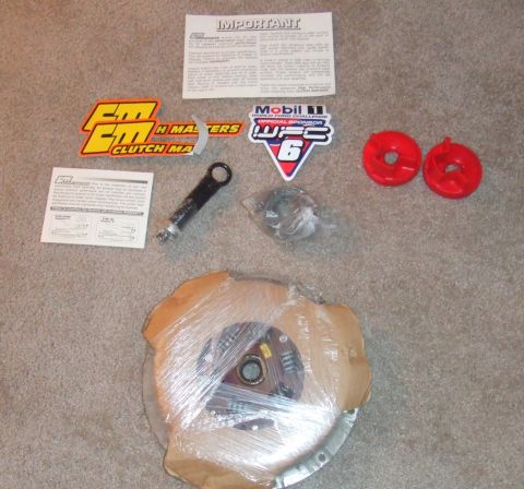1995 Ford Probe - This photo shows a clutch kit, including a clutch disc and pressure plate, along with various promotional stickers.