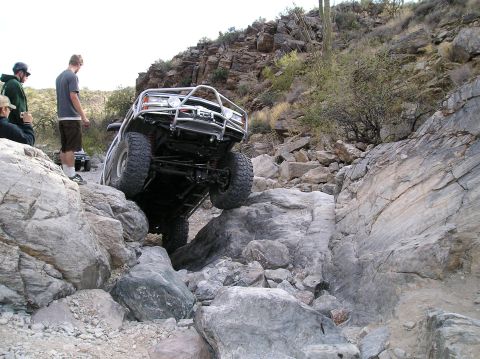 1993 Ford Bronco - A 1993 Ford Bronco tackles a challenging rocky trail with spectators watching.
