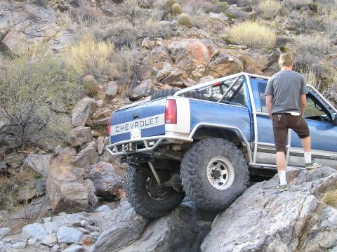 1993 Ford Bronco - A blue Chevrolet pickup truck is shown off-roading on a rocky, mountainous trail.