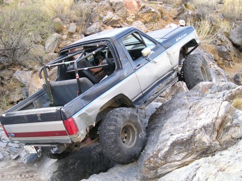 1993 Ford Bronco - This modified 1993 Ford Bronco navigates a rocky trail, its off-road capabilities with a reinforced roll cage and oversized tires.