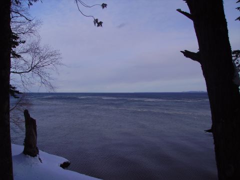 2000 Chevrolet Tahoe - A winter landscape features snow-covered ground and bare trees framing a vast, dark body of water under a muted sky.