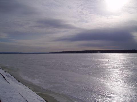 2000 Chevrolet Tahoe - A wide expanse of ice covers a body of water, with a dark tree line in the distance under a dramatic sky.