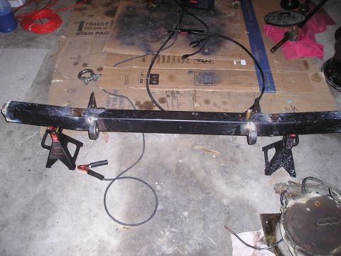 1986 Ford Bronco II - A custom bumper is supported by jack stands in a workshop setting.