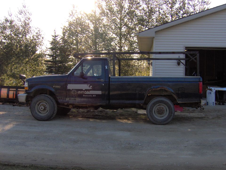 Side view of a 1995 Ford F-250 pickup truck with a rack and plow