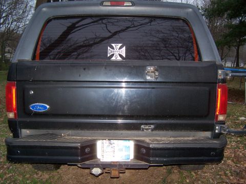 1992 Ford Bronco - Rear view of a 1992 Ford Bronco with a camper shell and a sticker on the rear window.