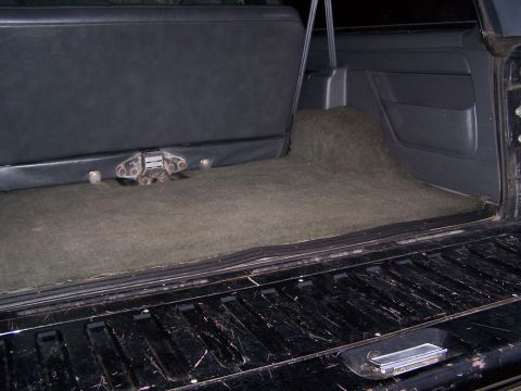 1992 Ford Bronco - The rear cargo area of the vehicle shows a carpeted floor and the underside of the rear seat with a latch.