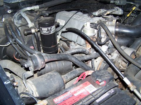 1992 Ford Bronco - Close-up view of a vehicle's engine bay, showing the battery and numerous engine parts.
