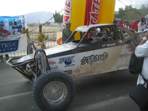 Silver Stroud Racing off-road buggy with Fox shocks staged beside Tecate arch