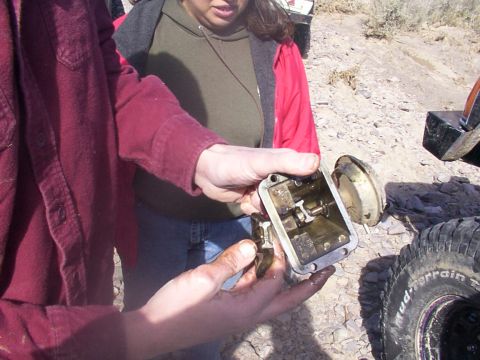 1978 Ford Bronco - Someone is holding a disassembled automotive part, possibly a gearbox or transfer case.