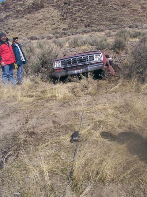 1978 Ford Bronco - A red pickup truck is stuck on a dry, grassy hillside with two people observing.