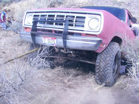 1978 Ford Bronco - This red pickup truck appears to be stuck in the dirt, with its front end angled downwards.