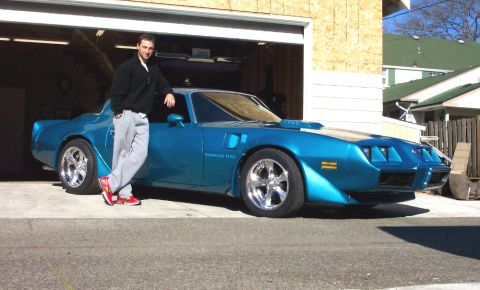 1979 Pontiac Trans Am - A man poses with his blue 1979 Pontiac Trans Am, which is parked in front of an open garage door.