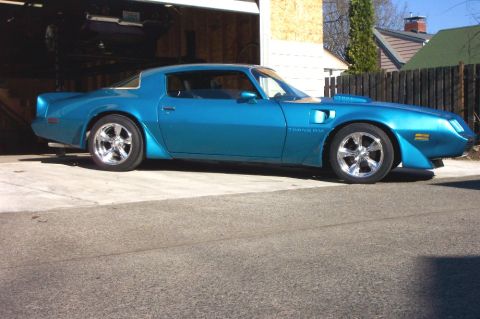 1979 Pontiac Trans Am - A blue 1979 Pontiac Trans Am is parked outside a garage, with another vehicle visible inside.