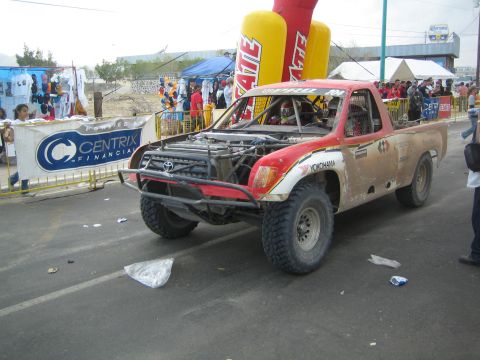 Dusty red and white off-road race truck with Yokohama tires under inflatable arch