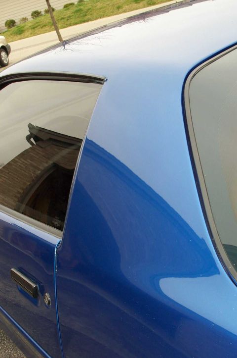 1990 Chevrolet Camaro - A blue 1990 Chevrolet Camaro is seen from the side, with a portion of the roof and rear window visible.