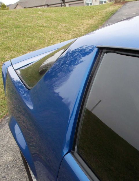 1990 Chevrolet Camaro - The distinctive rear quarter panel and window shape of a 1990 Chevrolet Camaro is visible in this close-up shot.