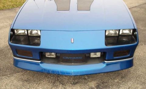 1990 Chevrolet Camaro - Front view of a blue 1990 Chevrolet Camaro, showing its distinctive grille and headlight design.