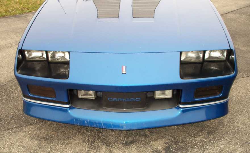 Blue 1990 Chevrolet Camaro front end with pop-up headlights and 'CAMARO' grille emblem