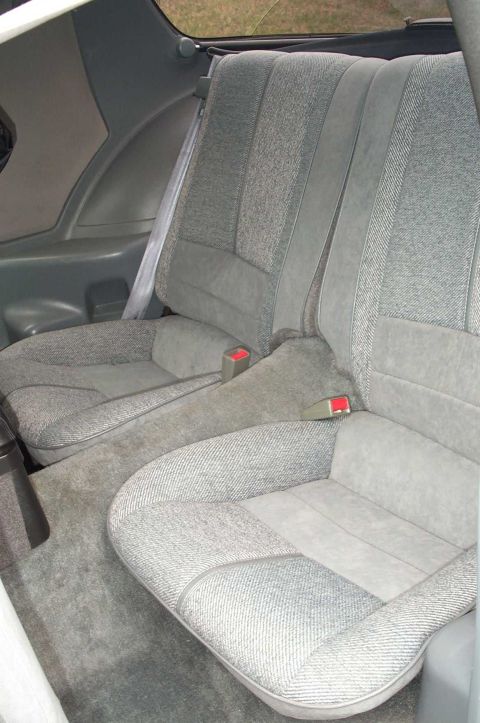 1990 Chevrolet Camaro - The interior of a vehicle shows the rear seats and carpeted floor.