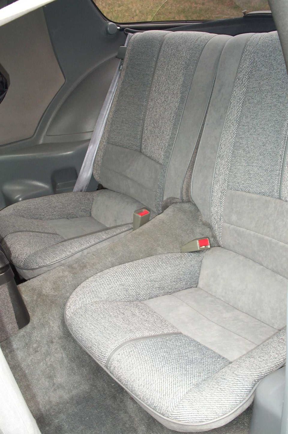 Gray fabric rear seats with gray carpet and red seatbelt buckles