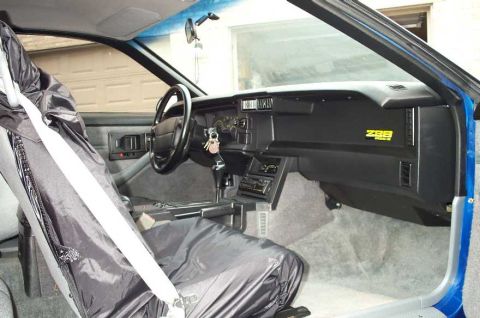 1990 Chevrolet Camaro - The interior of a 1990 Chevrolet Camaro Z28, showing the dashboard and driver's seat with a cover.