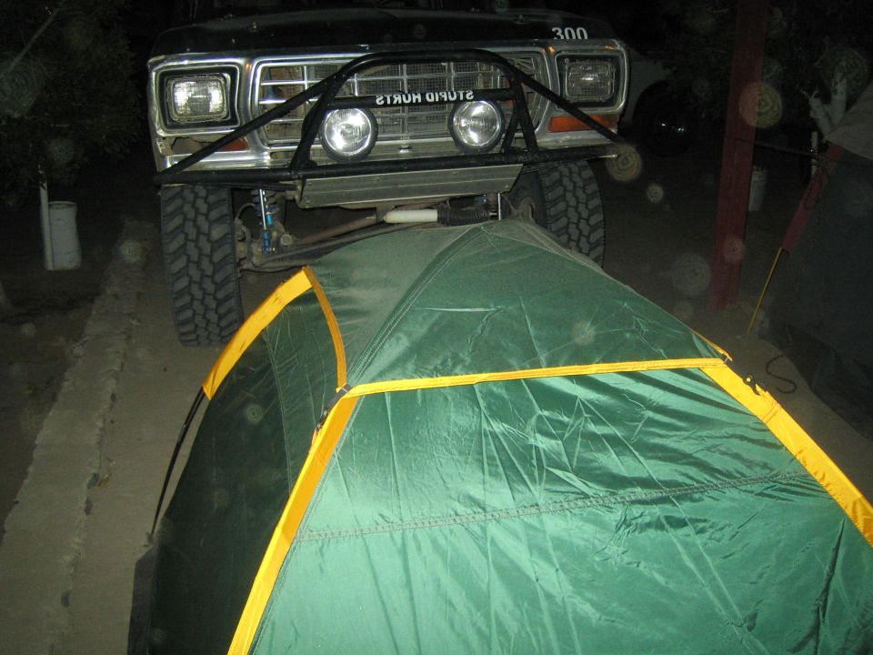 Front of a lifted truck parked over a green dome tent at night