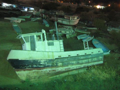 Several beached boats grounded on grassy shore at night, one large in front